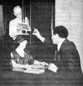 Houdini, his wife, and an assistant demonstrate a method of switching slates over a sitter's head that would be performed in a dark room during a seance.